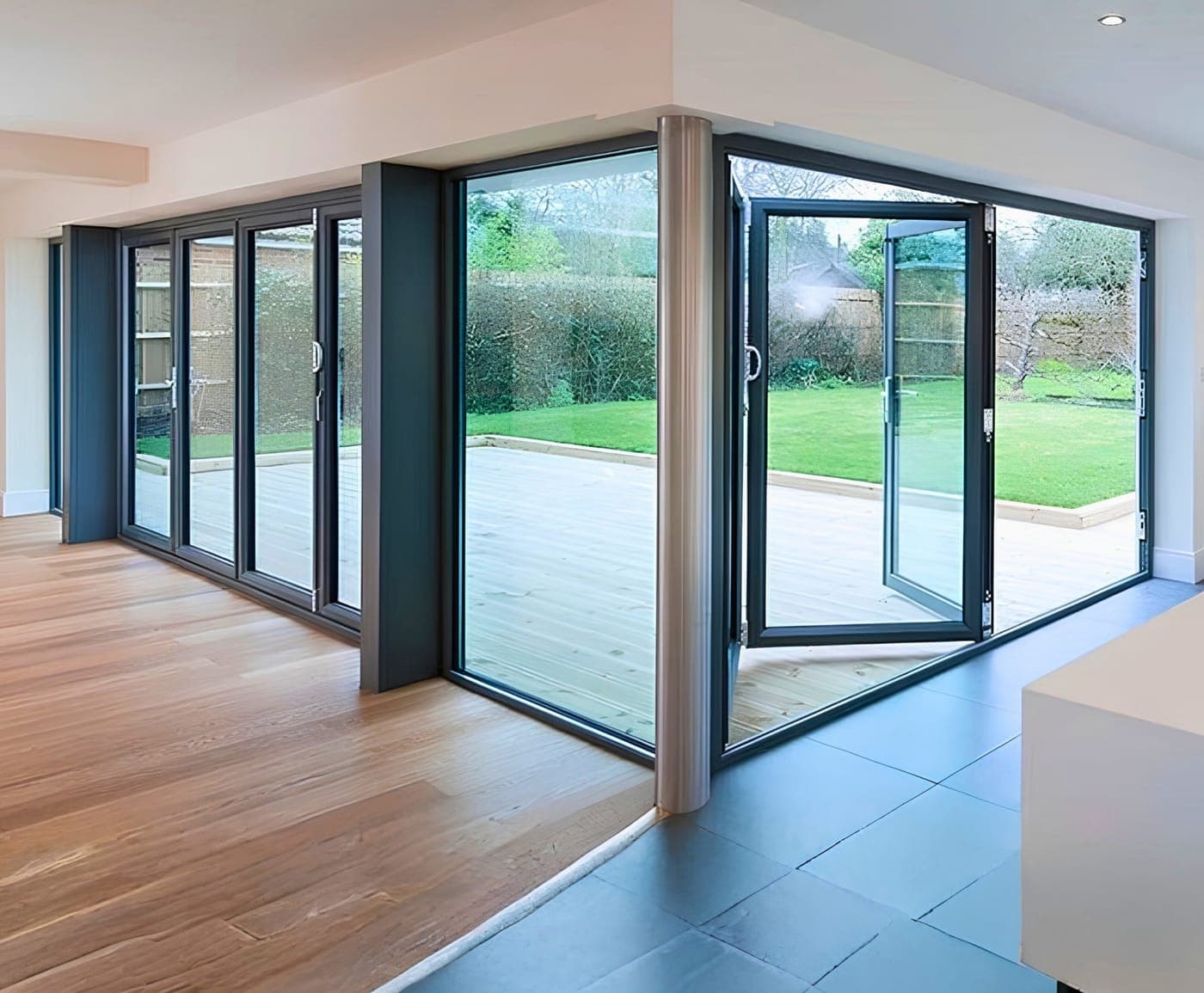 Dark-framed aluminium sliding doors meeting at a corner, opening onto a garden terrace