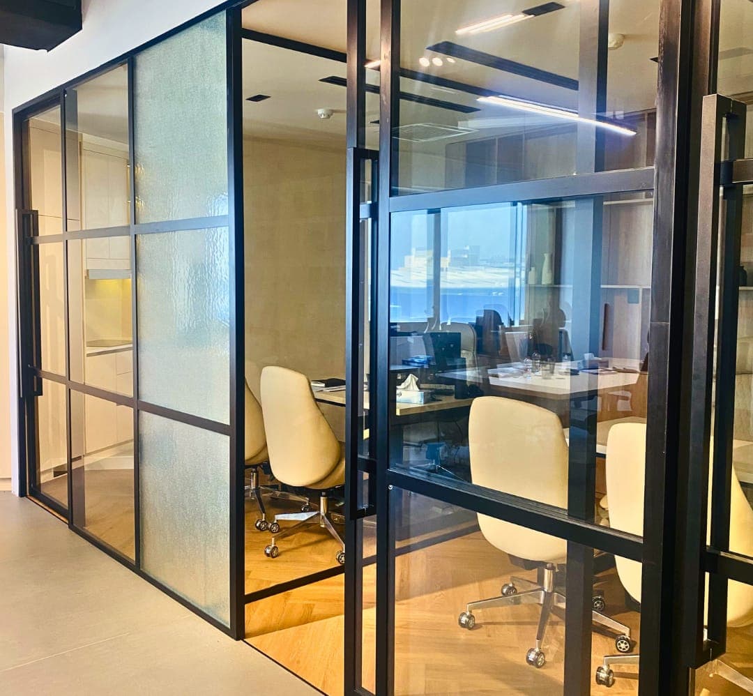 Black-framed glass partitions with fluted panels around an office meeting room